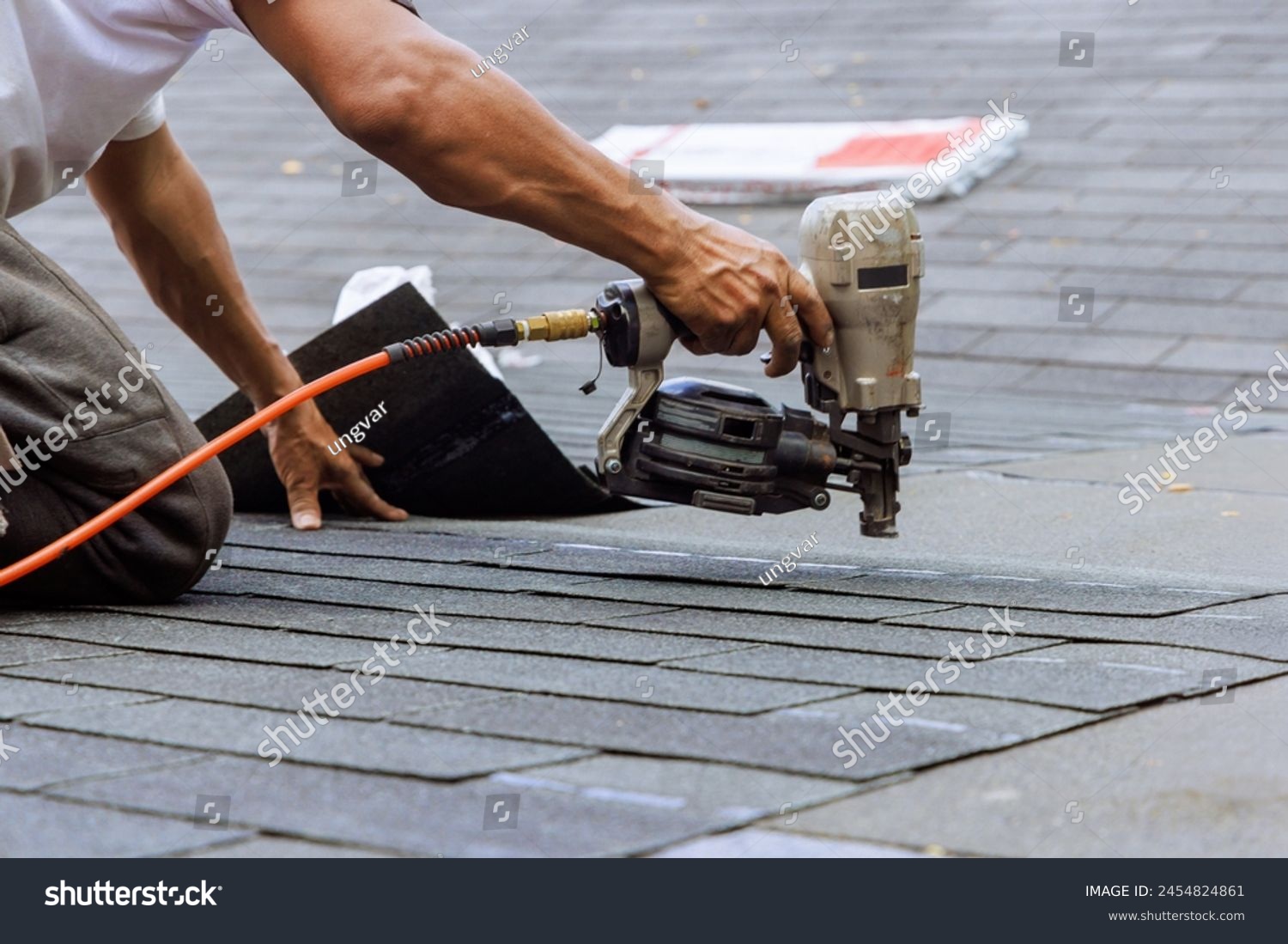 stock-photo-air-pneumatic-nail-gun-used-by-roofer-to-install-new-asphalt-bitumen-shingles-2454824861