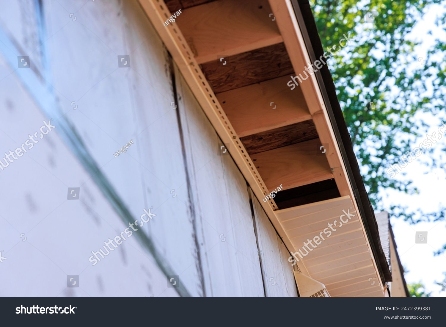 stock-photo-an-employee-installs-soffit-on-roof-corner-of-house-constructed-from-rafters-2472399381