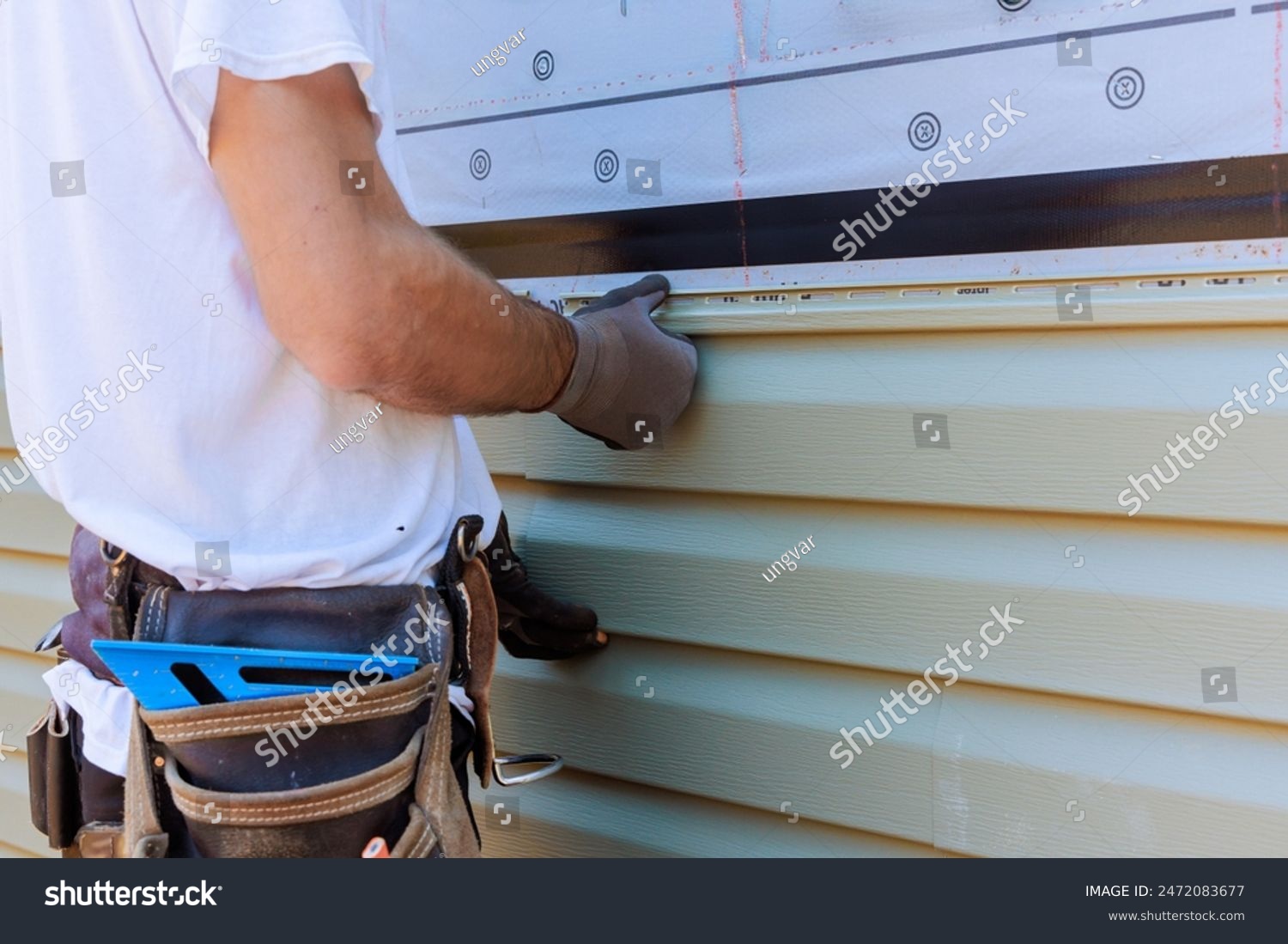 stock-photo-handyman-process-installing-vinyl-pvc-siding-during-construction-on-facade-new-home-2472083677