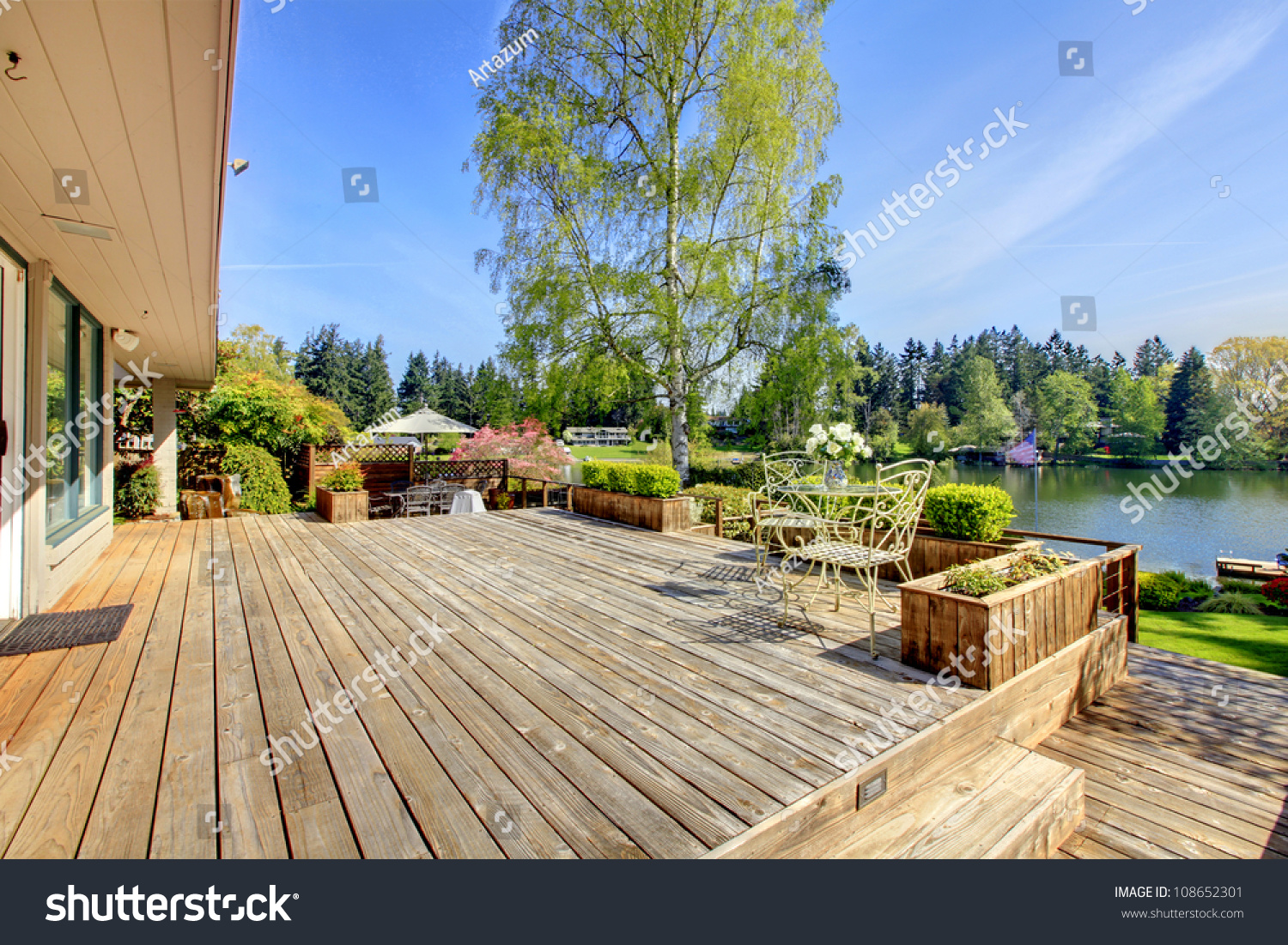 stock-photo-large-wood-deck-near-house-with-lake-and-spring-landscape-108652301